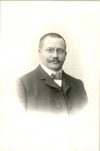 Porträt eines Mannes mit Kurzhaarschnitt, wilhelminischem Schnurrbart, Nickelbrille, Stehkragen, Fliege